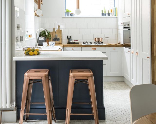 An open plan kitchen and breakfast bar with tall bar stools and copper coloured accent colour accessories.